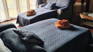 Une chambre avec deux lits, chacun recouvert d’une courtepointe bleue matelassée et agrémenté d’un coussin assorti, ainsi qu’une chaise avec un coussin.