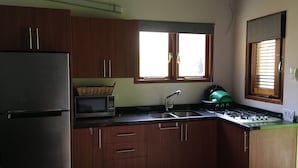 Una cocina con armarios de madera, un refrigerador de acero inoxidable, un microondas, un fregadero y una estufa a gas.