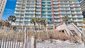 A tall, multi-story hotel with balconies and a central red vertical feature. - Grand Atlantic by Palmetto Vacations (Myrtle Beach)