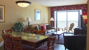 A living room with a dining table, chairs, a sofa, and a television. - Grand Atlantic by Palmetto Vacations (Myrtle Beach)