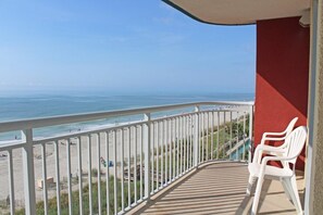 A balcony with a view of the beach and ocean.