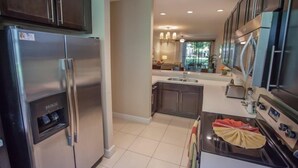 Una cocina moderna con electrodomésticos de acero inoxidable, una isla central y vistas al área de estar.
