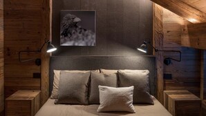 Un dormitorio acogedor con techo de madera, una cama grande con muchas almohadas y un cuadro enmarcado sobre la cama.