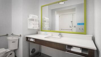 A modern bathroom with a white sink, a mirror with a green frame, and a toilet.