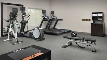 Un gimnasio con bicicletas estáticas, cintas de correr y una prensa de pesas.