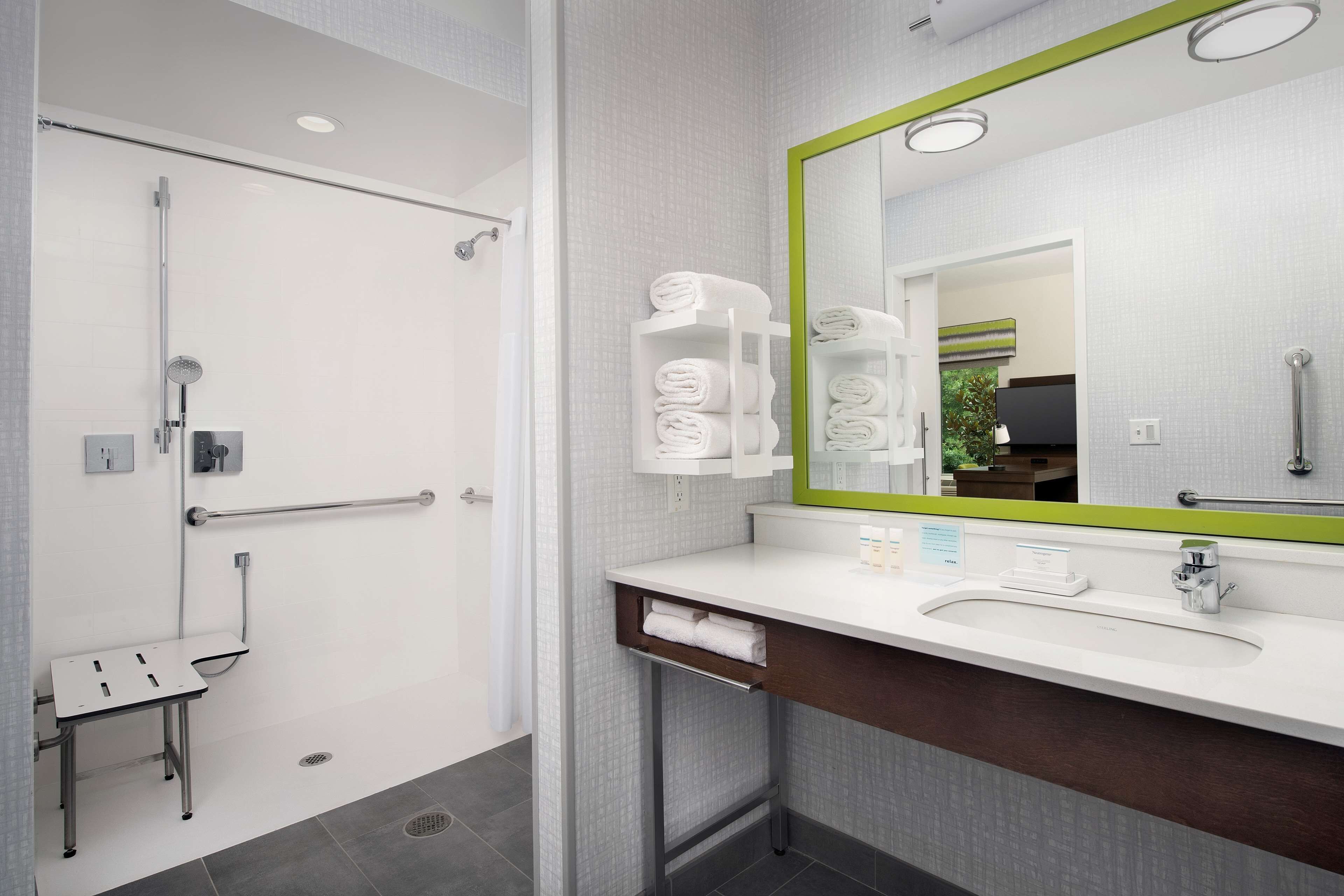 Een moderne badkamer met een douche, een wastafel met spiegel en een handdoekhouder.