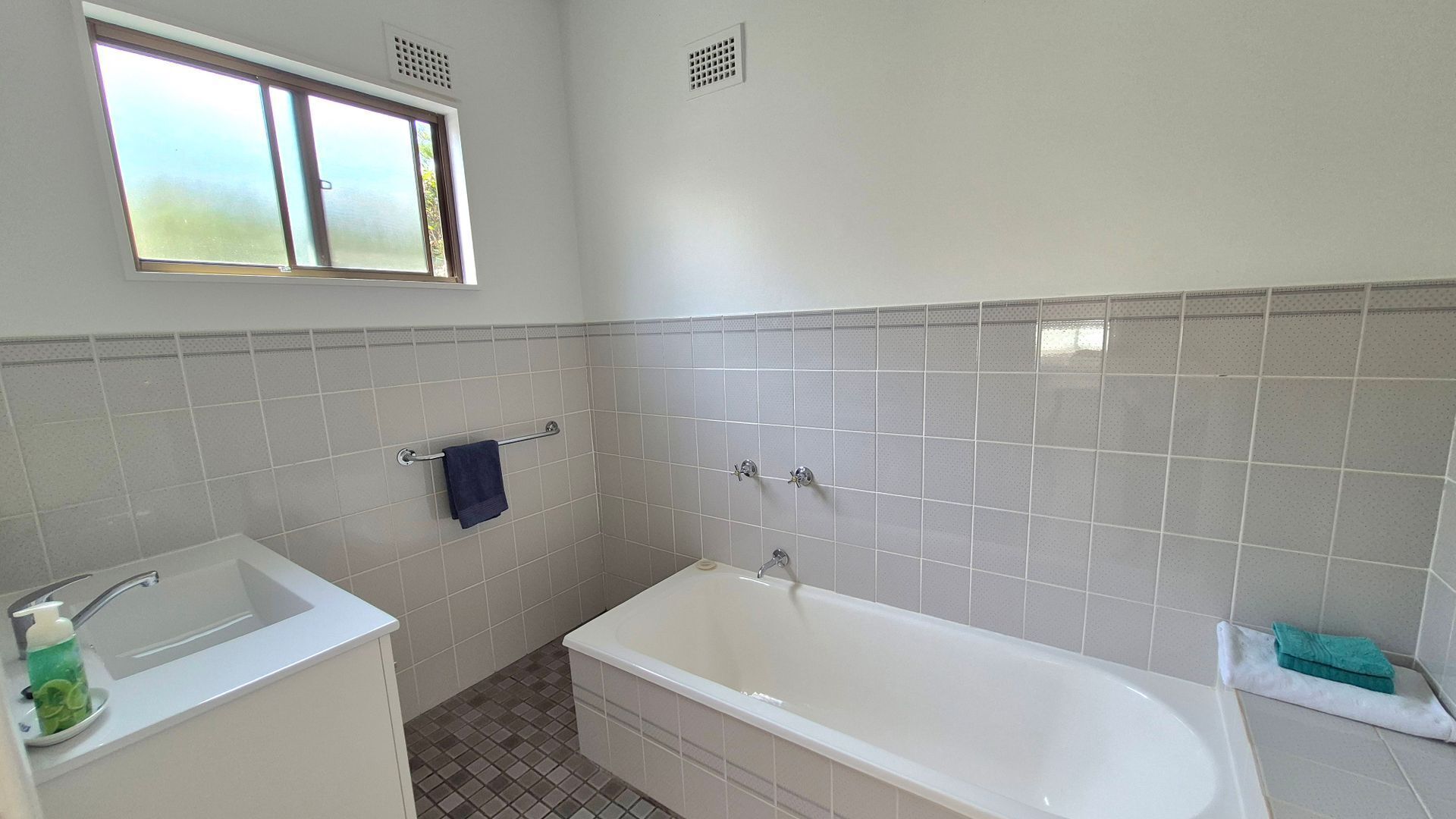 Une salle de bain avec une baignoire, un lavabo et une fenêtre.