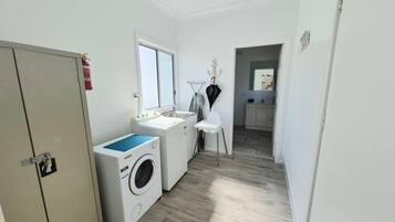 A laundry room with a washing machine, dryer, and ironing station.