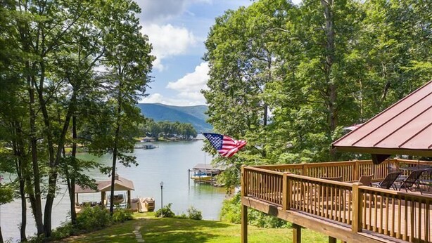 A lakeside deck with a view of the lake and mountains, a gazebo, and an American flag.