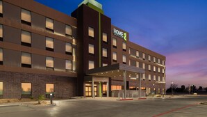 A modern hotel with a prominent "HOME 2" sign, a covered entrance, and a parking lot. - Home2 suites by Hilton, Carlsbad, New Mexico (Carlsbad)