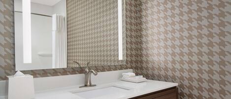 A bathroom with a large mirror, a sink, a towel rack, and a wooden vanity.