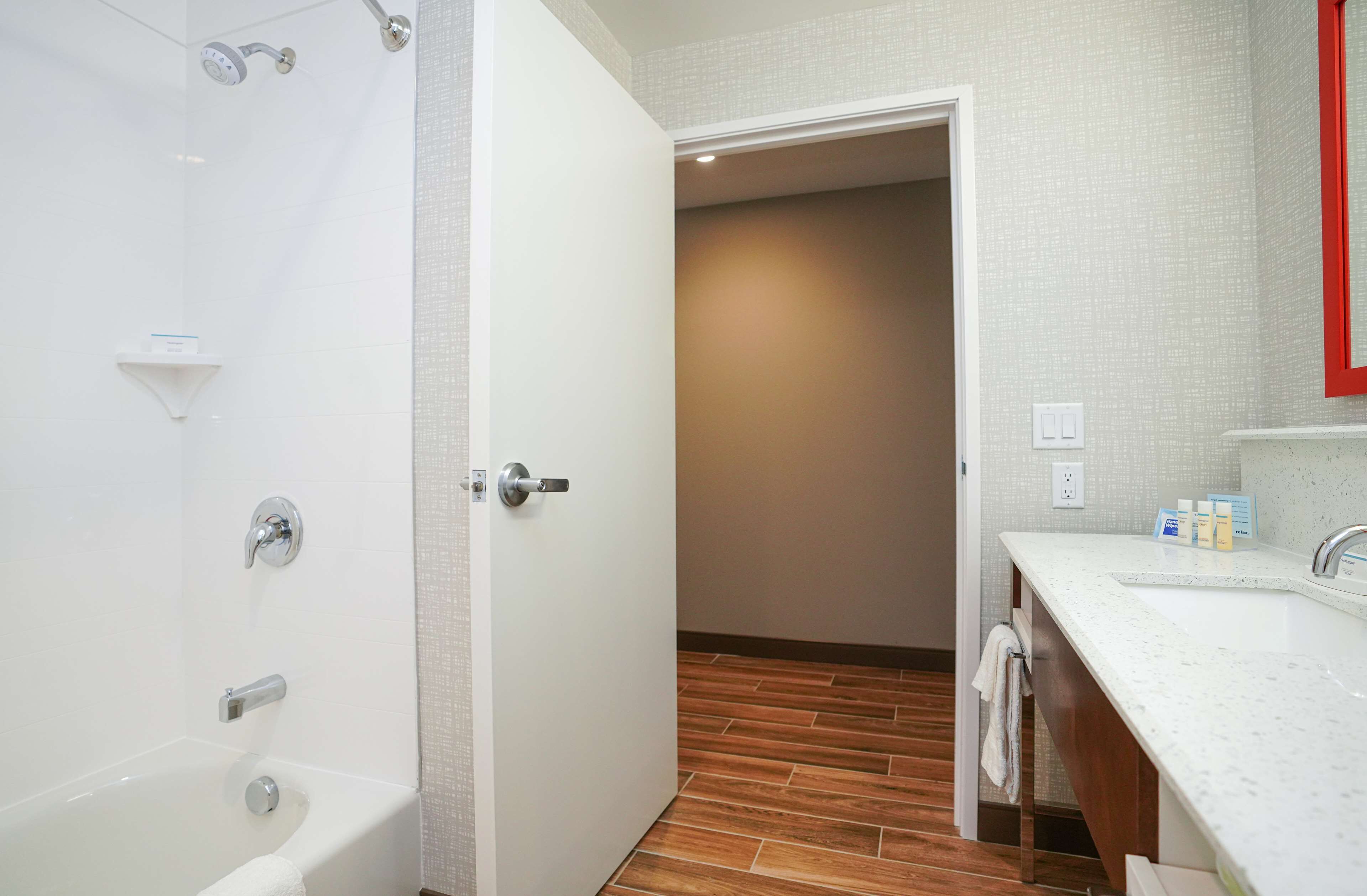 A modern bathroom with a bathtub, shower, and sink.