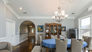 A dining area with a blue tablecloth, beige chairs, a chandelier, and a wooden cabinet with glass doors. - Luxury oasis with chef's dream kitchen and many outdoor spaces (Asheville)