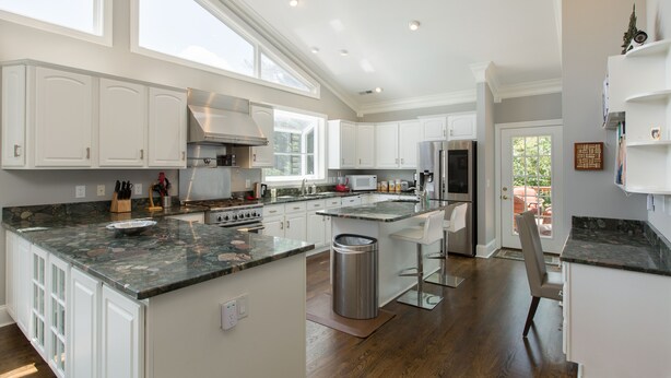 A spacious kitchen with white cabinets, granite countertops, and a large island. - Luxury oasis with chef's dream kitchen and many outdoor spaces (Asheville)