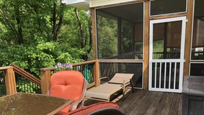 A wooden deck with a table and chairs, surrounded by lush greenery. - Luxury oasis with chef's dream kitchen and many outdoor spaces (Asheville)