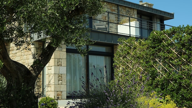 Un edificio moderno con paredes de piedra, ventanas grandes y un balcón.