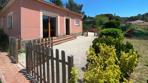 A pink villa with a gravel driveway, wooden fence, and a well-maintained garden with yellow shrubs. - Club Villamar - Nice and cozy villa with private pool, located in a quiet area with nice views (Macanet de la selva)