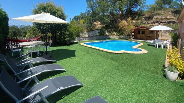 A backyard with a swimming pool, artificial grass, lounge chairs, and umbrellas. - Club Villamar - Nice and cozy villa with private pool, located in a quiet area with nice views (Macanet de la selva)