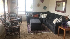 A living room with a sofa, two armchairs, a coffee table, and a rug.