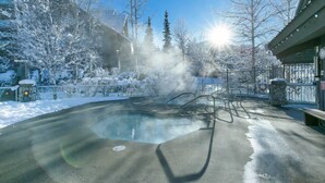 A heated outdoor pool surrounded by snow-covered trees and a building. - Peaceful Forest View A/C Pool BBQ Netflix | The Suite Life Whistler at Aspens (Whistler)