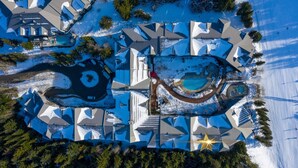 An aerial view of a resort with a distinctive star-shaped pool, multiple buildings, and a clear blue sky. - Peaceful Forest View A/C Pool BBQ Netflix | The Suite Life Whistler at Aspens (Whistler)