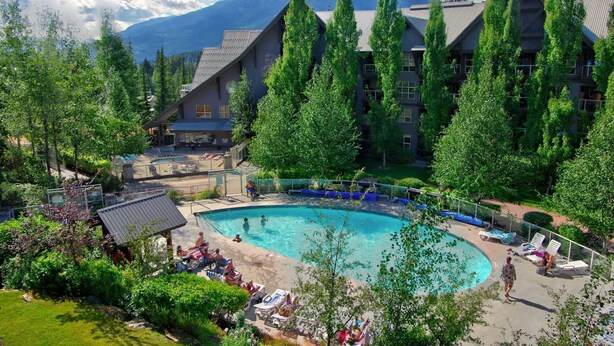 A resort with a large pool surrounded by trees and mountains in the background. - Peaceful Forest View A/C Pool BBQ Netflix | The Suite Life Whistler at Aspens (Whistler)