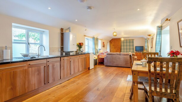 Una cocina amplia con armarios de madera, un comedor con mesa y sillas, y una sala de estar con sofá.
