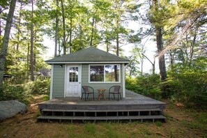 A small cabin with a porch, two chairs, and a table. - Family Retreat on Squam Lake, Tennis, Kayaks, Paddleboards, Dock. (Moultonborough)