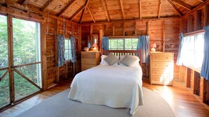 Ein Schlafzimmer einer Holzhütte mit Bett, Kommode und Fenster.