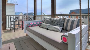 Een overdekt terras met een zachte zithoek, een klein tafeltje en stoelen.