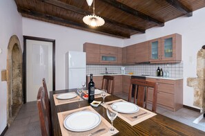 A dining area with a table set for four, featuring a kitchen with cabinets and a backsplash.
