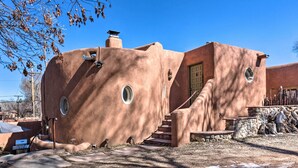 A stucco building with a circular window, a door, and a staircase leading to the entrance. - Chic Adobe-Style Bungalow in Historic Santa Fe! (Santa Fe)