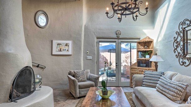 A cozy living room with a fireplace, a sofa, a coffee table, and a chandelier. - Chic Adobe-Style Bungalow in Historic Santa Fe! (Santa Fe)