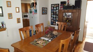 A dining room with a wooden table, chairs, and a cabinet with photos. - Cozy Cottage close to the Lake (Harbert)