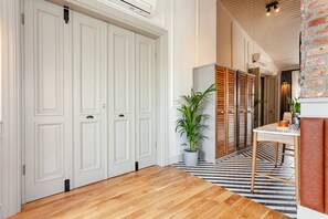 A hallway with wooden flooring, white doors, a potted plant, and a table with a mug.