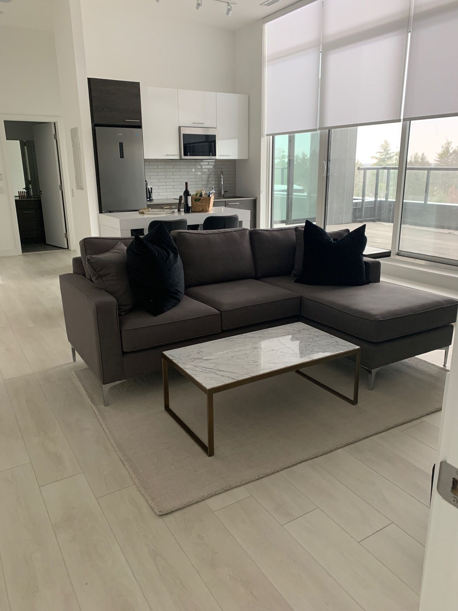 Una sala de estar moderna con un sofá seccional, una mesa de centro de mármol y un ventanal con vistas al exterior.