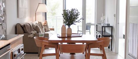 A modern kitchen with a dining area, wooden furniture, and a large window.