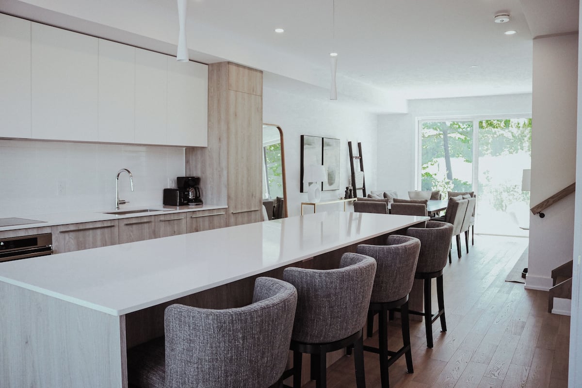 Una cocina moderna con una isla grande, taburetes de bar y un comedor con vistas al exterior.