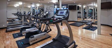 Un gimnasio con cintas de correr, bicicletas estáticas y máquinas de pesas.