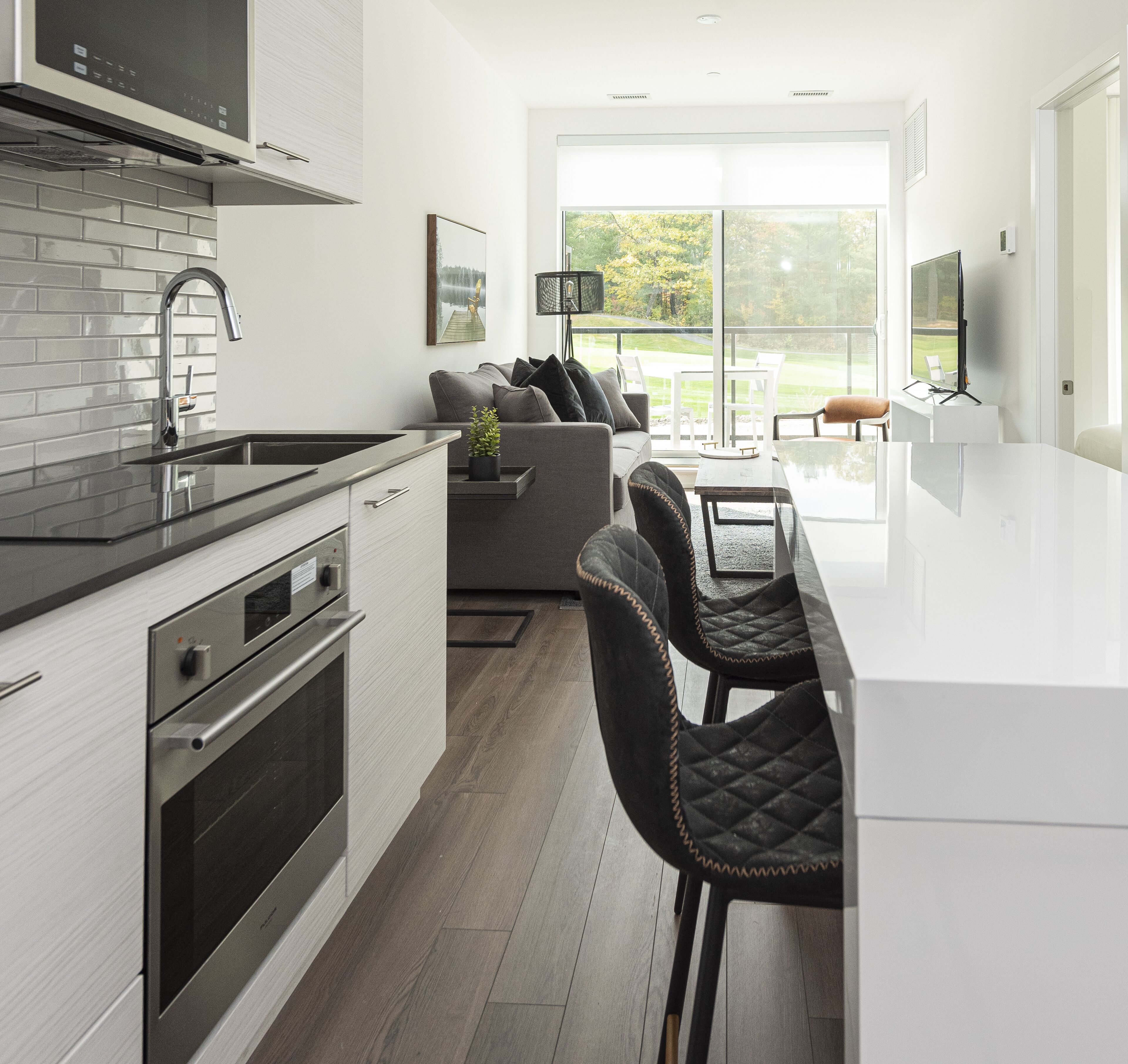 A modern kitchen with a central island, built-in oven, and stainless steel appliances.