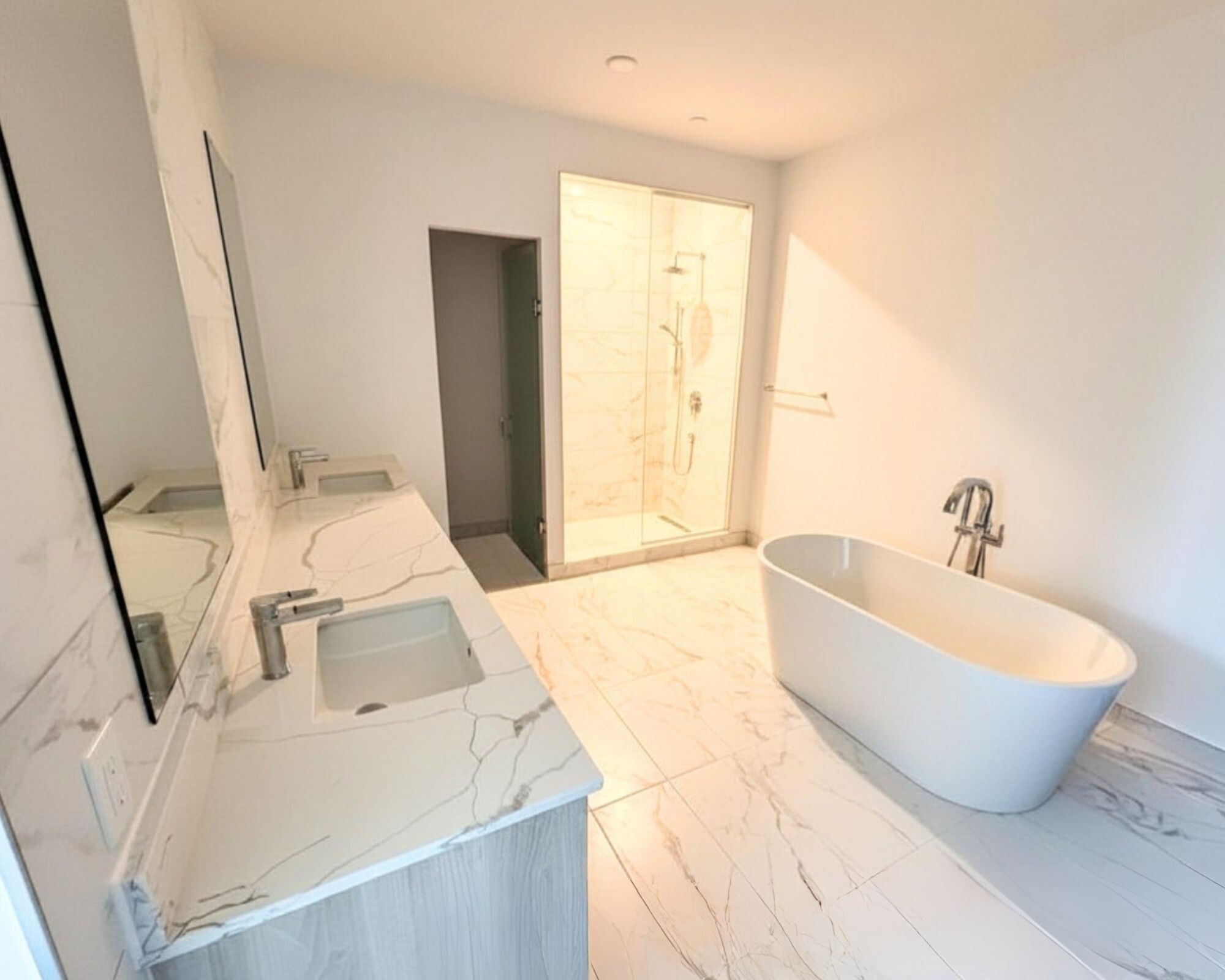 Ein modernes Badezimmer mit einer freistehenden Badewanne, einem großen Spiegel und einer begehbaren Dusche.