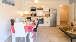 Eine moderne Küche mit weißen Schränken, einem Edelstahl-Kühlschrank und einem Essbereich mit Tisch für zwei Personen.