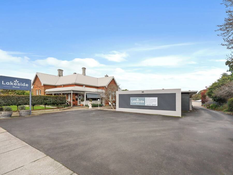 A Lakeside Motel with a brick building, a clear sky, and a well-maintained driveway.