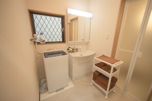 A compact bathroom with a washing machine, a sink, a mirror, and a towel rack. - Kanegafuchi House (Sumida-ku)