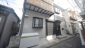 A residential building with a tiled exterior, a small balcony, and a garage door. - Kanegafuchi House (Tokyo)