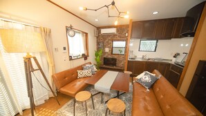 A modern living room with a brown leather sofa, a wooden coffee table, and a dining area. - Kanegafuchi House (Tokyo)