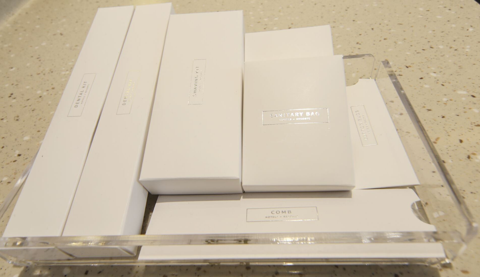 A clear plastic storage box containing several white boxes labeled with hotel names and services.