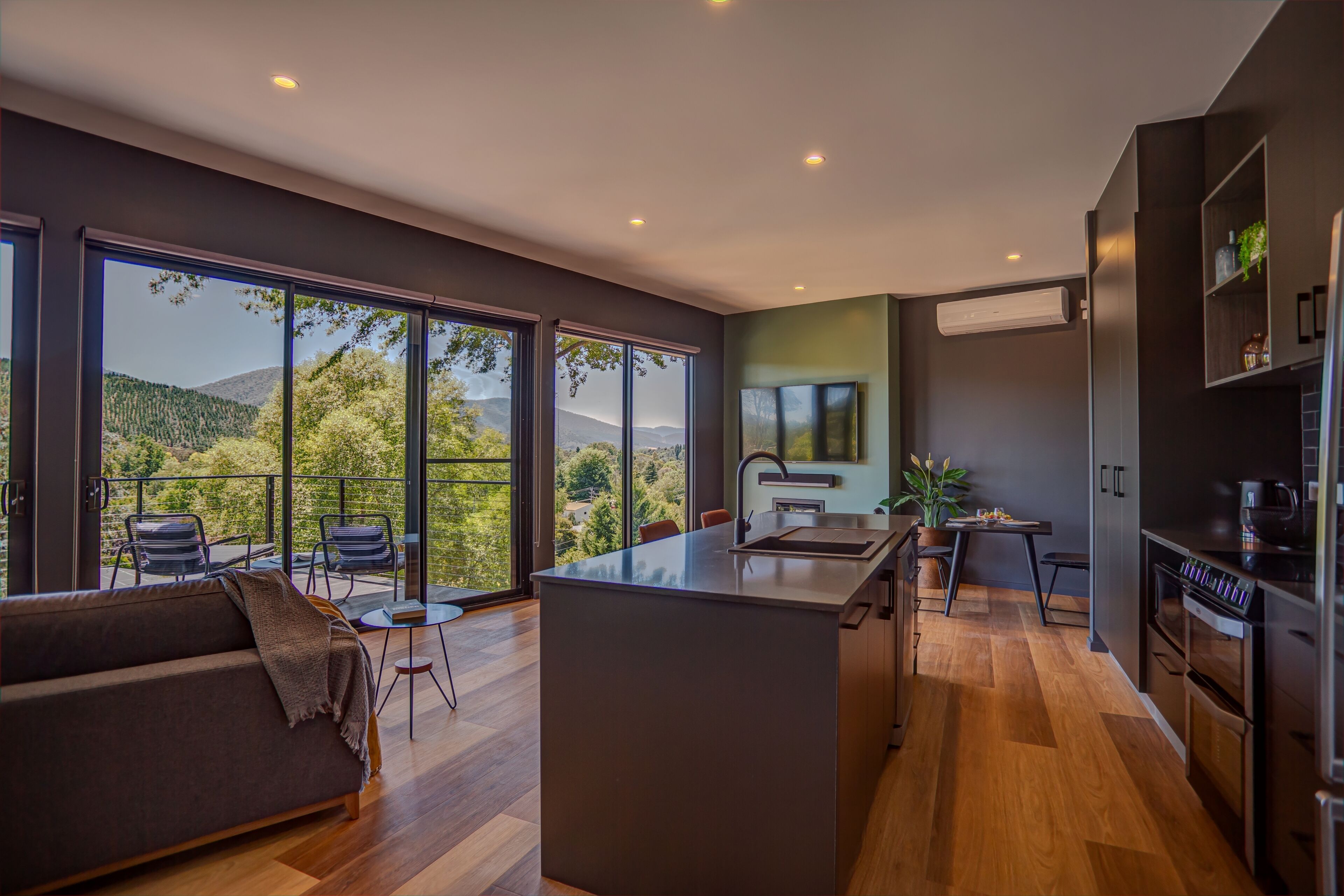 A modern kitchen with a central island, large windows, and a view of the outdoors.