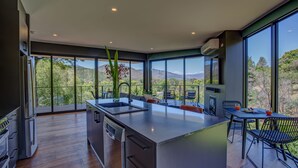 A modern kitchen with a large island, built-in appliances, and large windows offering a view of the outdoors. - The View Bright (Bright)
