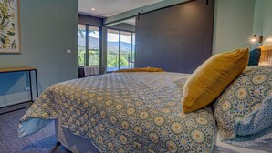 A bedroom with a large bed, a view of the outdoors, and a sliding door. - The View Bright (Bright)